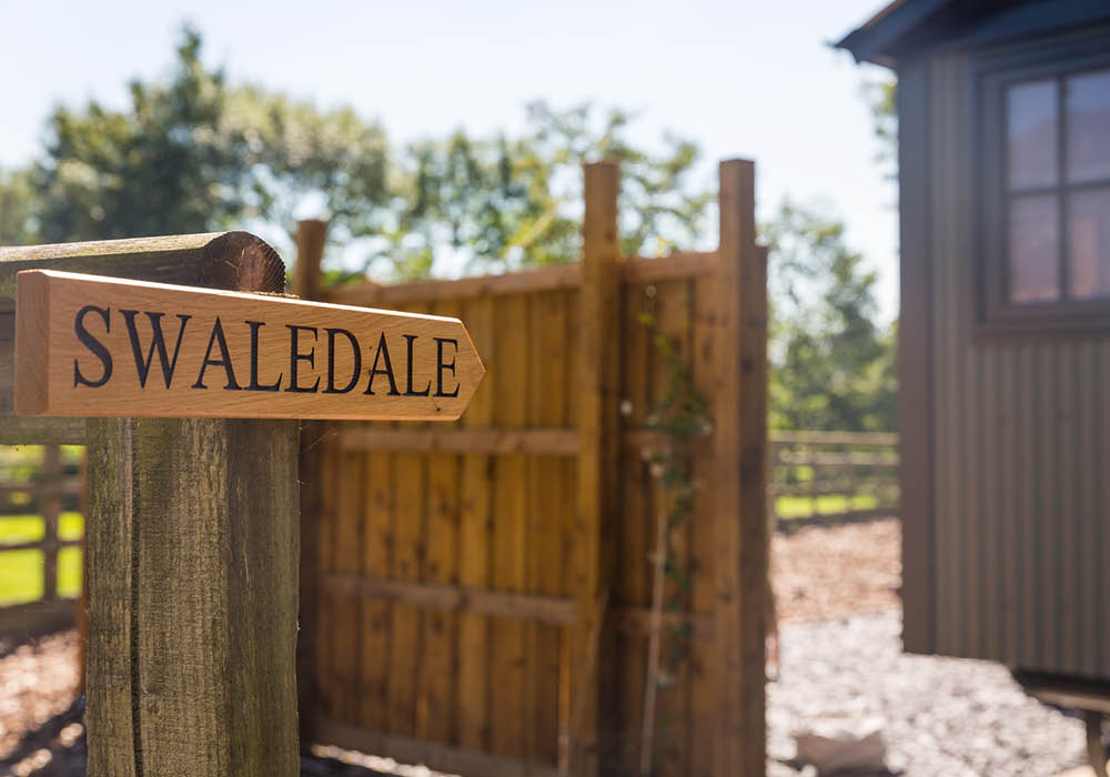 a wooden sign srewed to a fence post with the name Swaledale stamped on it in large black letters