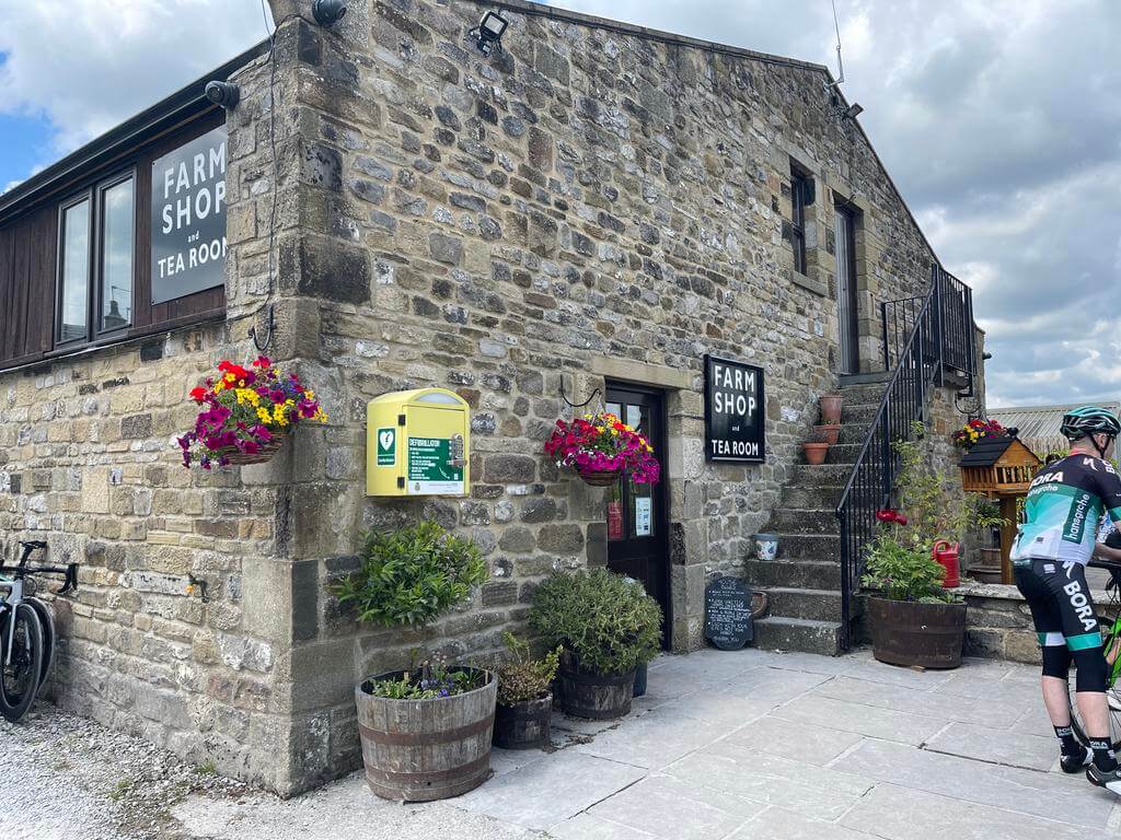 an outdoor shot of Town End Farm Shop, a much visited destination in the Yorkshire Dales - a cyclist clad in green and black lycra outside