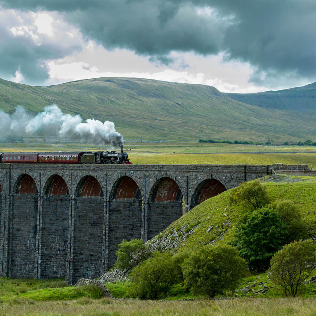 a steam train powers over ribblehead viaduct