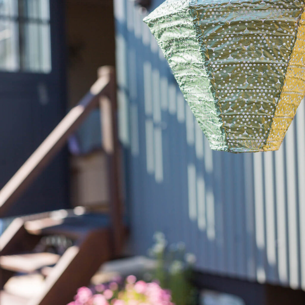 a green paper lantern hanging on the side of a shepherd hut