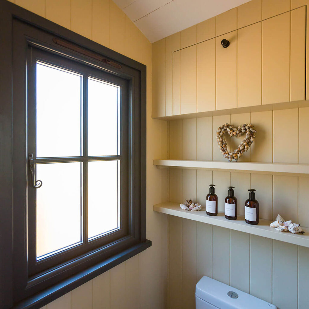 a frosted window in the wood panelled shower room of a Settledown shepherd hut