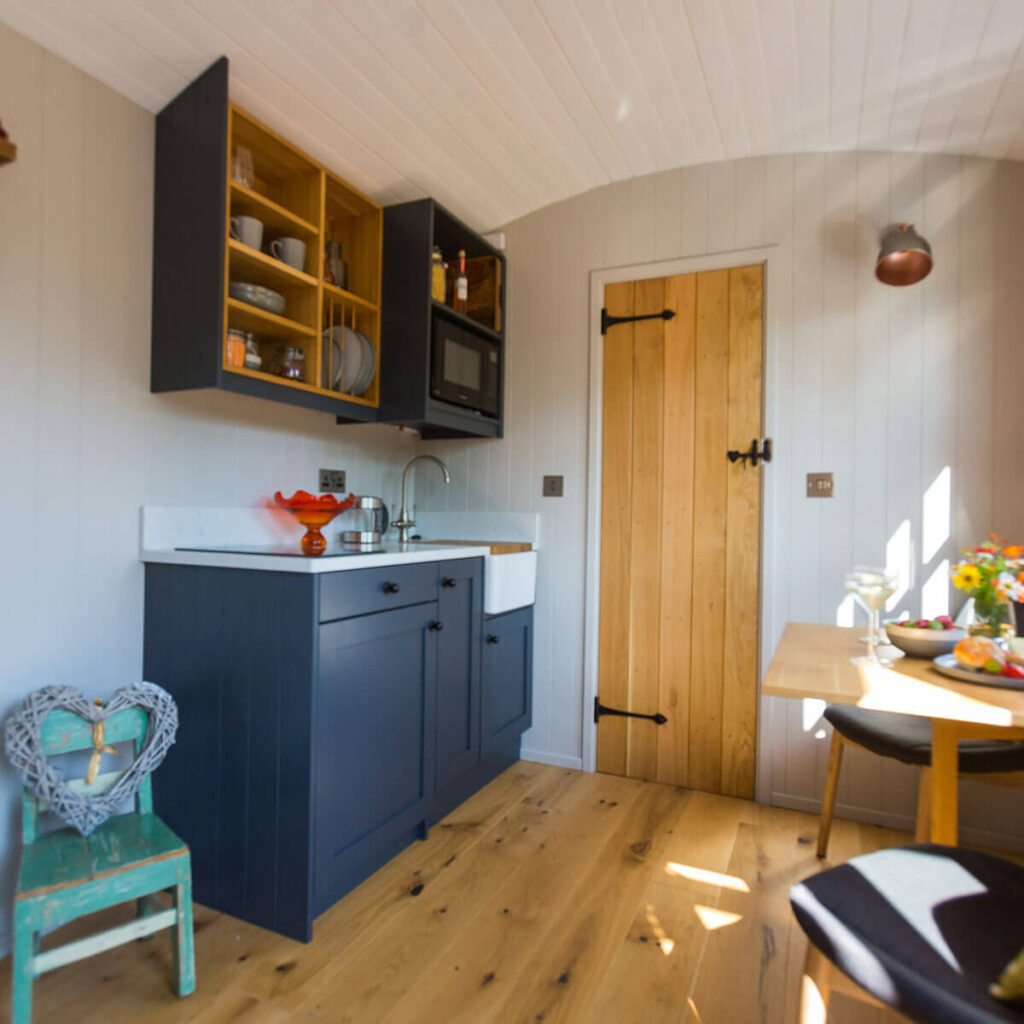 a slightly out of focus view of the kitchen and dining area inside one of the beautifully fitted out shepherd huts at Settledown retreats