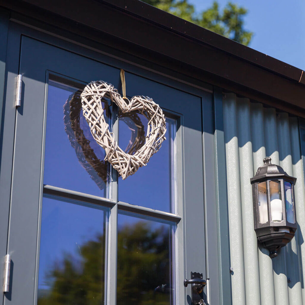 a wicker heart hanging from the door of a shepherd hut